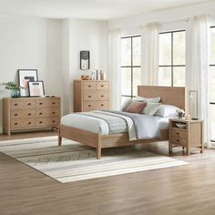 a bedroom scene with focus on the bed and dressers in the foreground, and an area rug on the floor