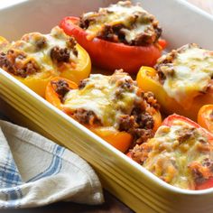 stuffed bell peppers in a casserole dish on a wooden table with a napkin