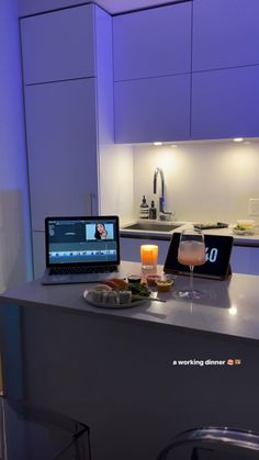 a laptop computer sitting on top of a kitchen counter next to a plate of food