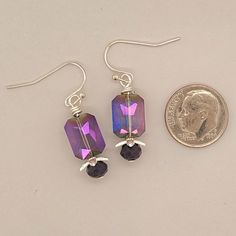 Plush Purple Earrings have an iridescent transparent purple rectangle glass bead atop a 5-petal silver finish bead cap and faceted matte purple rondelle. earrings dangle from ball end ear wires in silver finish. Designed and created by Angela at Takeen Arts Studio. Item E1627. Purple Czech Glass Earrings With Faceted Beads, Nickel-free Purple Glass Jewelry, Modern Purple Earrings For Party, Purple Rectangular Jewelry For Party, Silver Crystal Earrings For Jewelry Making, Silver Czech Glass Crystal Earrings With Ear Wire, Purple Czech Glass Jewelry With Matching Earrings, Nickel-free Purple Czech Glass Jewelry, Silver Glass Drop Crystal Earrings