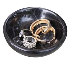 several rings in a black bowl on top of each other with white diamonds around them