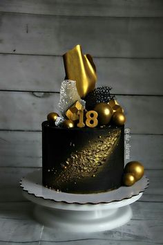 a black and gold birthday cake with decorations