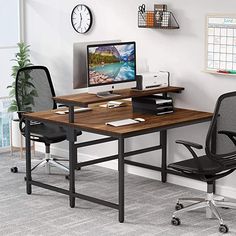 a desk with two chairs and a computer on it in front of a wall mounted clock