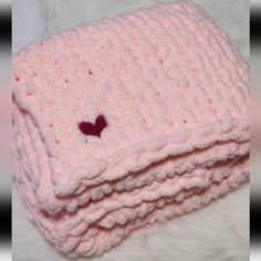 a pink knitted blanket with a heart on it