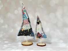 two small christmas trees made out of fabric on wooden bases with white boke background