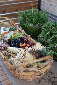 a wicker basket filled with assorted cheeses and meats on a table