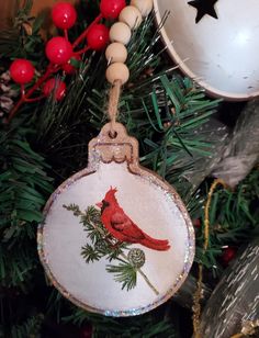 a red cardinal ornament hanging from a christmas tree with baubles on it