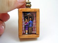 a miniature figurine is being held up to show the man and woman inside