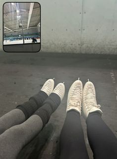 two people are sitting on the ground with their feet up and one is wearing white sneakers