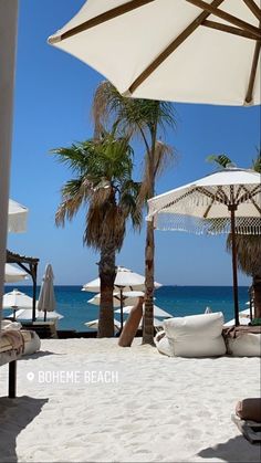 umbrellas and lounge chairs on the beach with palm trees