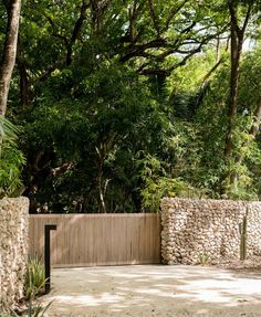 a stone wall and gate in front of trees