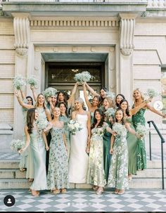 a group of women standing next to each other in front of a building holding bouquets