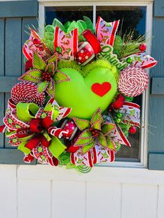 a green heart wreath with candy canes and candies on the front window sill