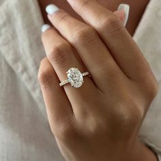 a woman's hand with a diamond ring on her left hand and the other hand holding an engagement ring