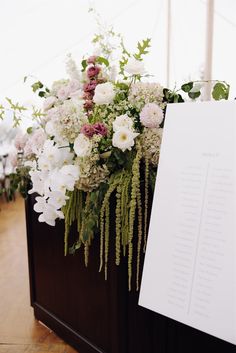 flowers and greenery are arranged on the back of a wooden box at a wedding reception