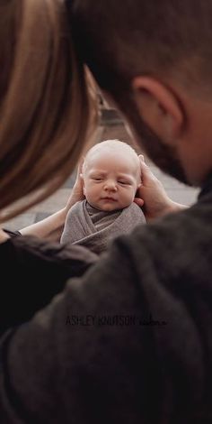 a man holding a baby up to his face in front of a woman's face