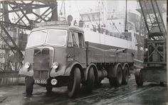 an old black and white photo of a truck with a large boat in the background