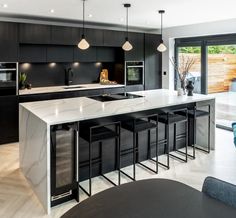 a modern kitchen with marble counter tops and black cabinets, along with bar stools