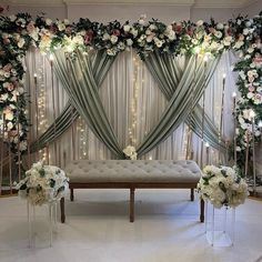 a wedding ceremony setup with flowers and candles on the side wall, along with tulle drapes