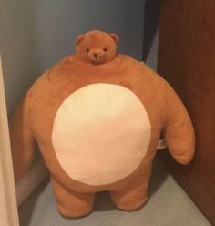 a large brown teddy bear sitting on top of a toilet