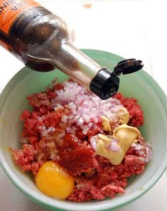 a bowl filled with meat and onions next to a bottle