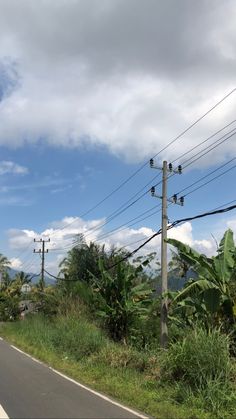 an empty road with power lines and telephone poles in the background on a cloudy day