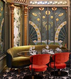 an elegant dining room with red chairs and gold accents on the walls, along with art deco - inspired wallpaper