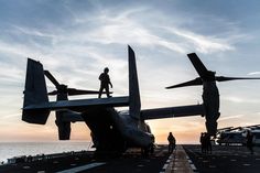 an airplane on the flight deck of an aircraft carrier at sunset with people standing around it