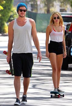 a man and woman walking down the street with skateboards