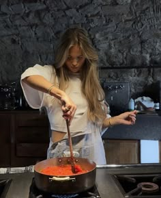 a woman stirring food in a pot on the stove