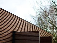 the side of a building with wooden slats on it's sides and trees in the background