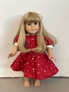 a doll with long blonde hair wearing a red dress and white stars on it's chest