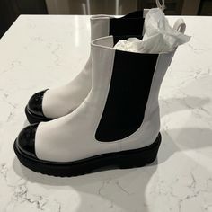 Chanel Lug Boot In White And Black With Patent Black Cap Toe Never Been Worn Comes With Original Box And Dust Bags. White Calf Leather Boots With Round Toe, Chic White Boots With Flat Heel, Chic White Flat Heel Boots, White Calf Leather Boots Medium Width, White Medium Width Calf Leather Boots, Designer White Leather Boots, Designer White Boots With Round Toe, Designer White Round Toe Boots, White Chanel Boots