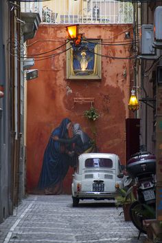 an old car parked in front of a building with a painting on it's side