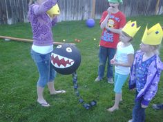 children in costumes are playing with balls on the lawn and one girl is wearing a paper crown