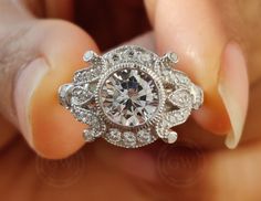 a close up of a person's hand holding a diamond ring