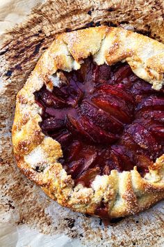 a pie with some fruit on it sitting on top of a piece of parchment paper