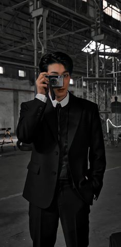 a man in a suit holding a camera up to his face