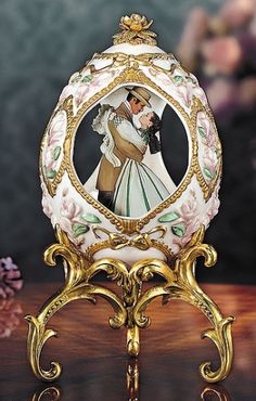 an ornately decorated egg with a bride and groom in the center on a wooden table