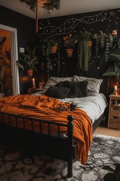 a bed with an orange blanket on top of it next to potted plants and candles