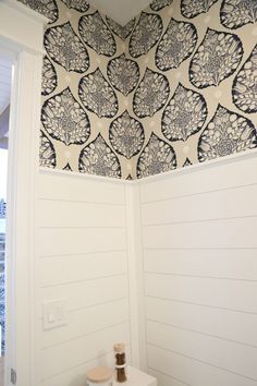 a white toilet sitting in a bathroom next to a wallpapered ceiling with black and white designs on it