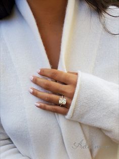 a close up of a person wearing a white sweater with a diamond ring on their finger