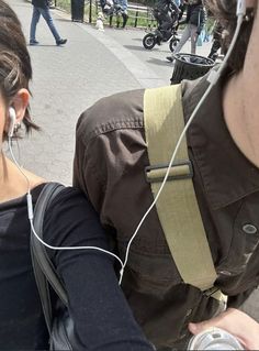 a man with ear buds on his ears is listening to music while standing next to a woman