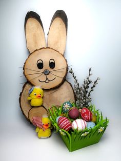 a wooden bunny sitting next to an easter basket filled with eggs