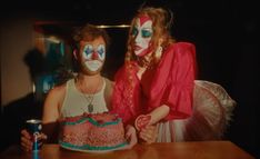 two women with painted faces are sitting at a table and one is holding a cake