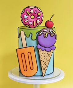 a colorful cake with an ice cream cone, doughnut and fork on the top