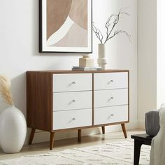 a white and brown dresser sitting in a living room next to a painting on the wall