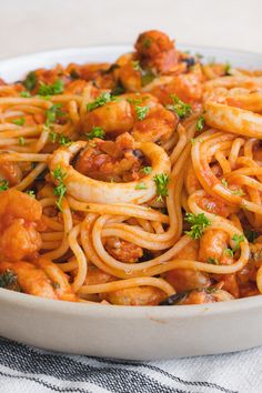 spaghetti marinara with shrimp and parsley in a white bowl