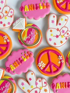 decorated cookies with peace signs, flowers and hearts are displayed on a white tablecloth