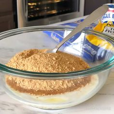 a glass bowl filled with dry ingredients on top of a white marble counter next to an oven